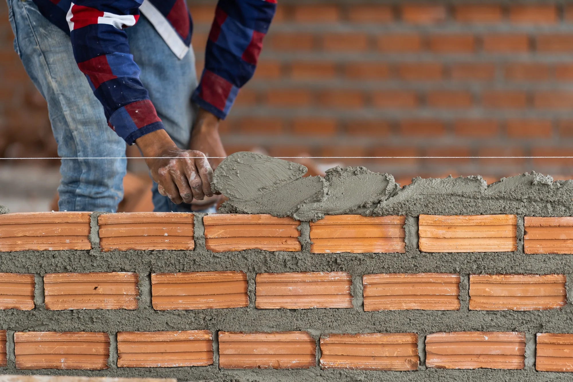 Closeup hand professional construction worker laying bricks in new industrial site